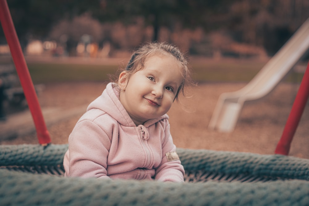 a little girl sitting on a playground