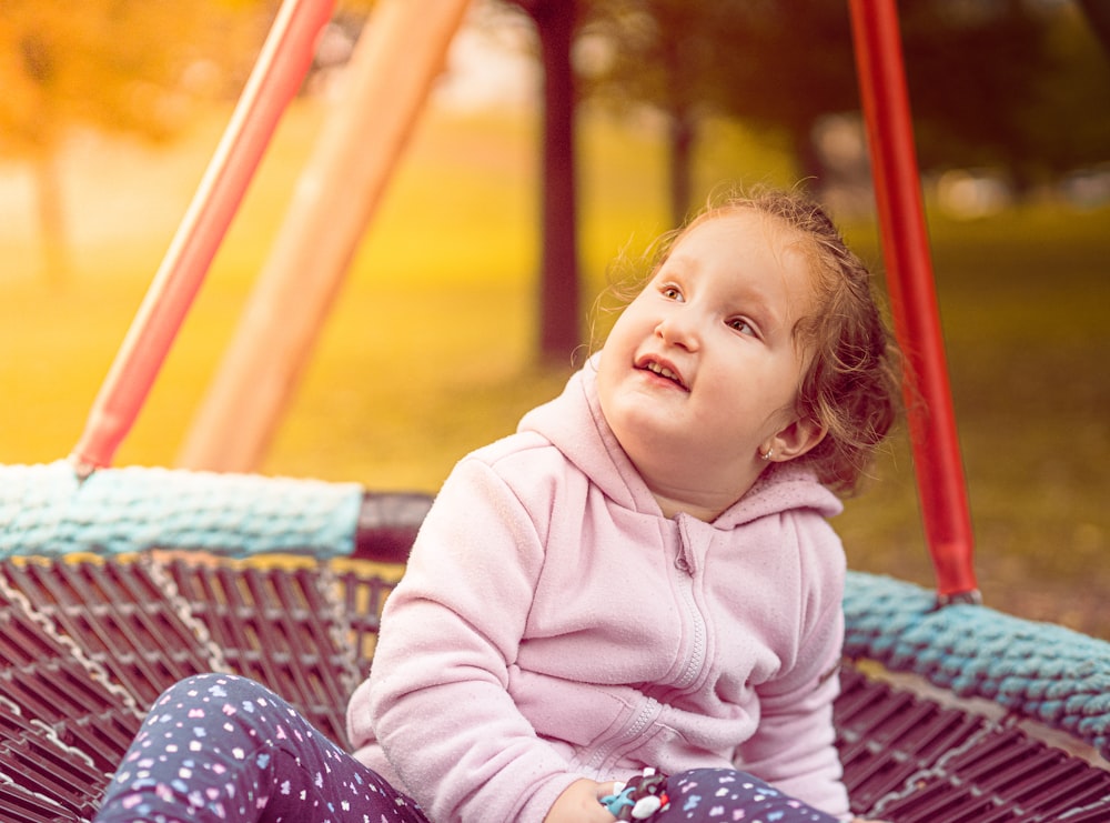 a little girl sitting on a swing