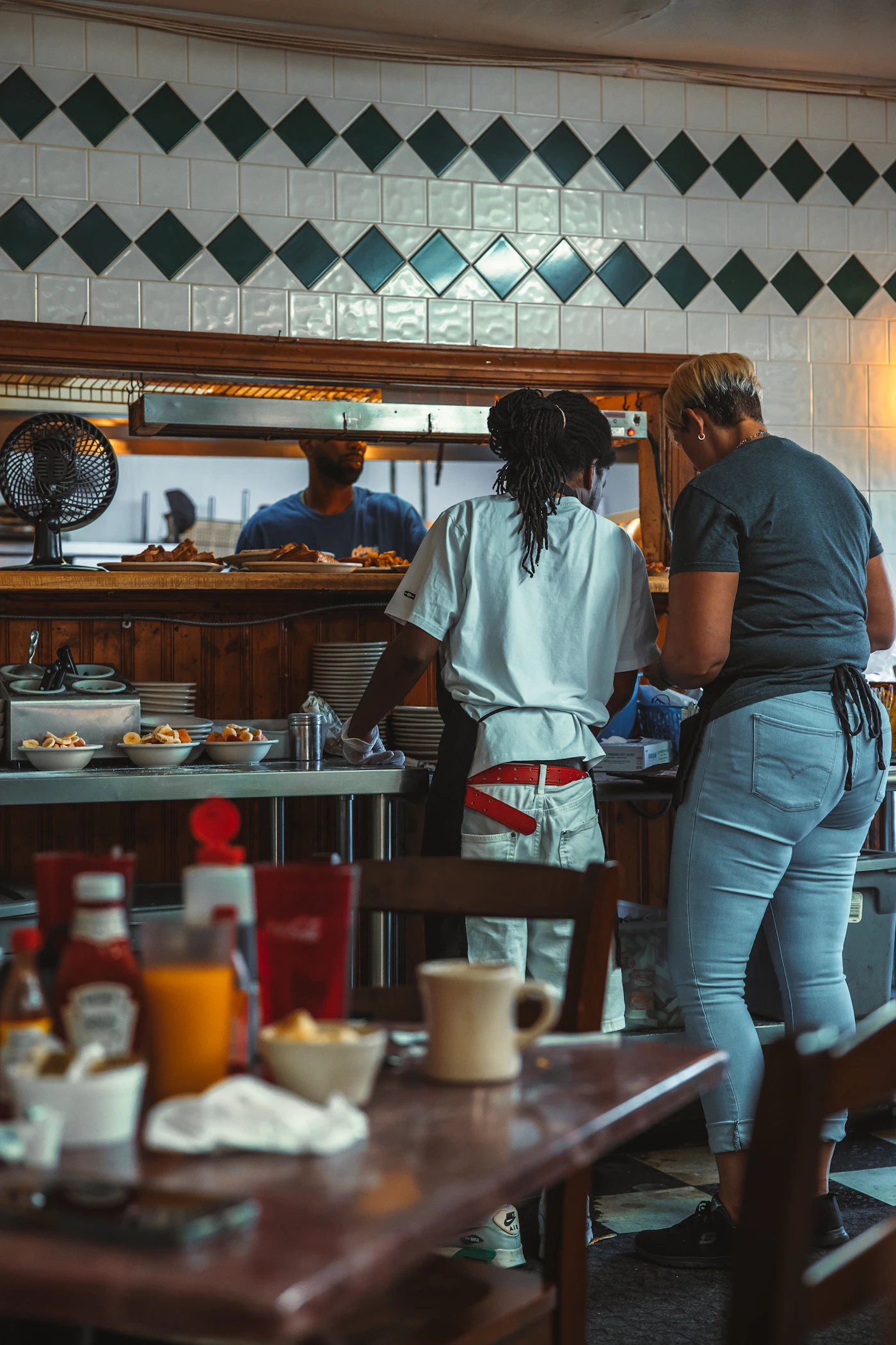 Restaurant team passing finished dishes across the kitchen counter