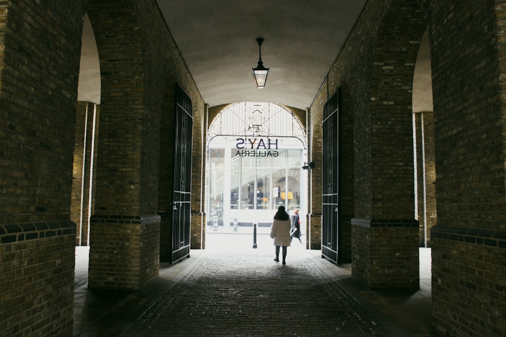 a couple of people walking in a brick hallway