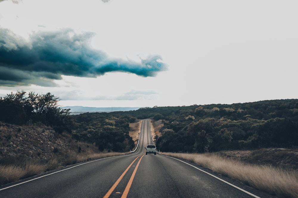 a road with a car on it and a cloud of smoke above