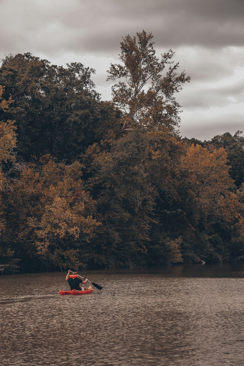 a couple people in a kayak on a river with trees in the background