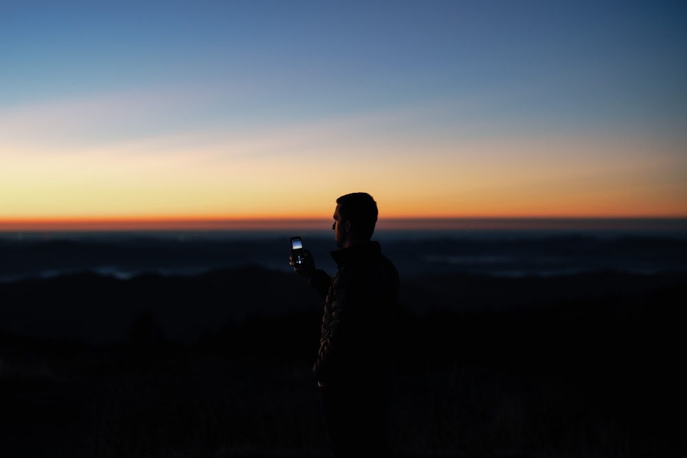 a person taking a picture of the sunset