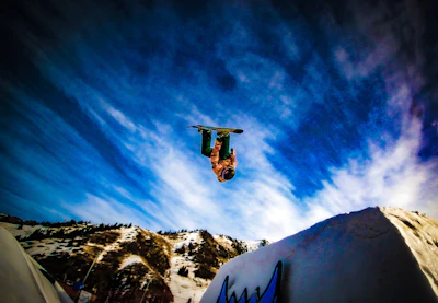 Dynamic shot of a rider mid-air performing a grab trick with snowy peaks behind