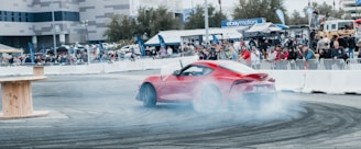 a red and white race car on a track with a crowd watching