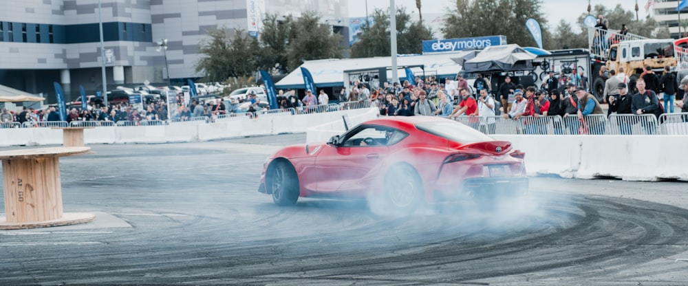 a red and white race car on a track with a crowd watching