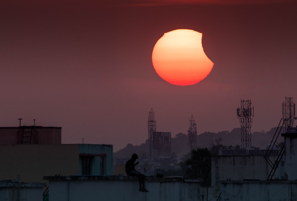 a person sitting on a roof looking at the sun