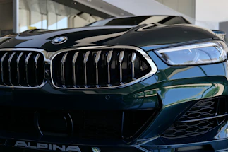 A sleek, dark-toned close-up of a luxury car's grille illuminated by subtle lighting.