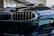 A close-up view of a luxury car's front grille and headlight. The image features sleek, reflective surfaces with intricate design elements, showcasing a modern and sophisticated style.