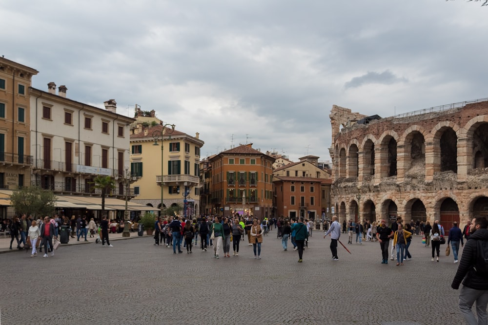 a group of people walking in a courtyard with buildings in the background