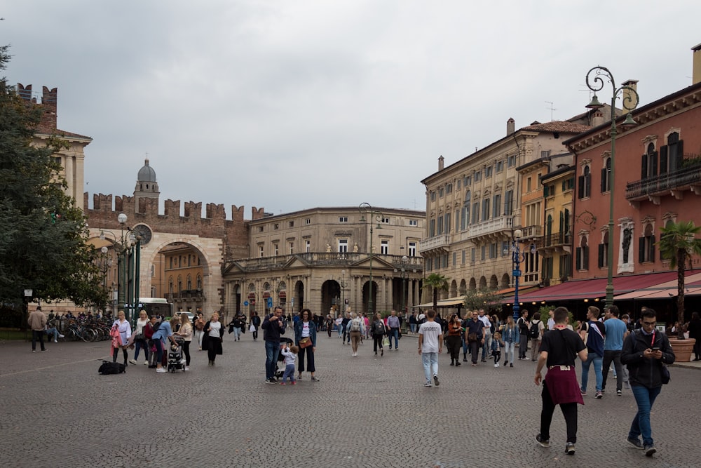 a group of people walking in a plaza with buildings in the background