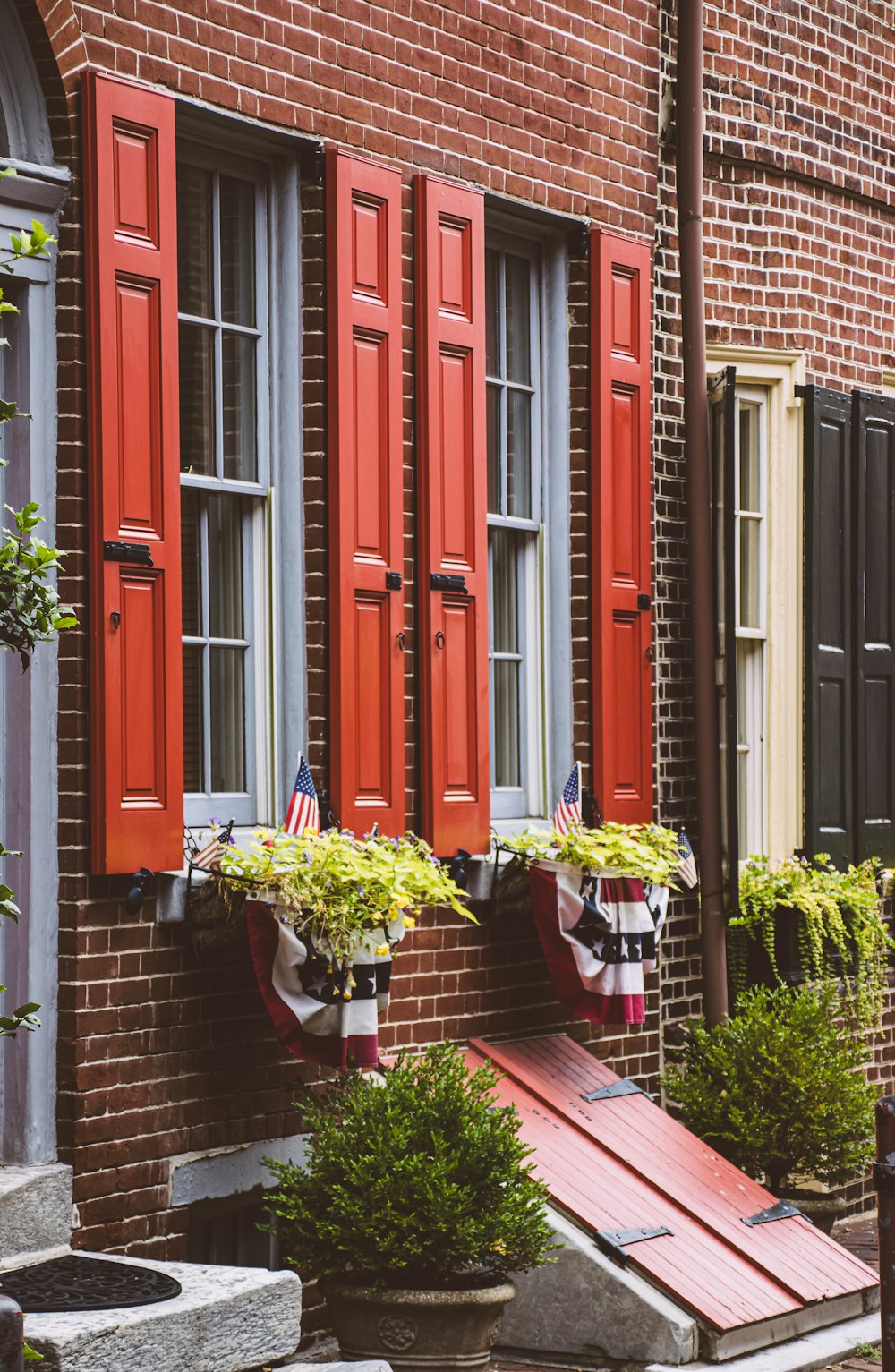 a brick building with red shutters and a flag on the window