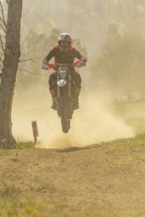 Close-up of a motocross rider mid-air during a jump on a dirt track.
