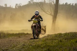 A Honda dirt bike kicking up dust on a rugged trail in the countryside.