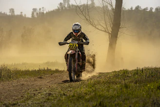 Dynamic shot of a rider wearing full protection gear speeding through a dusty trail.