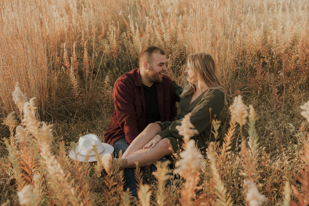 a man and woman sitting in a field of tall grass