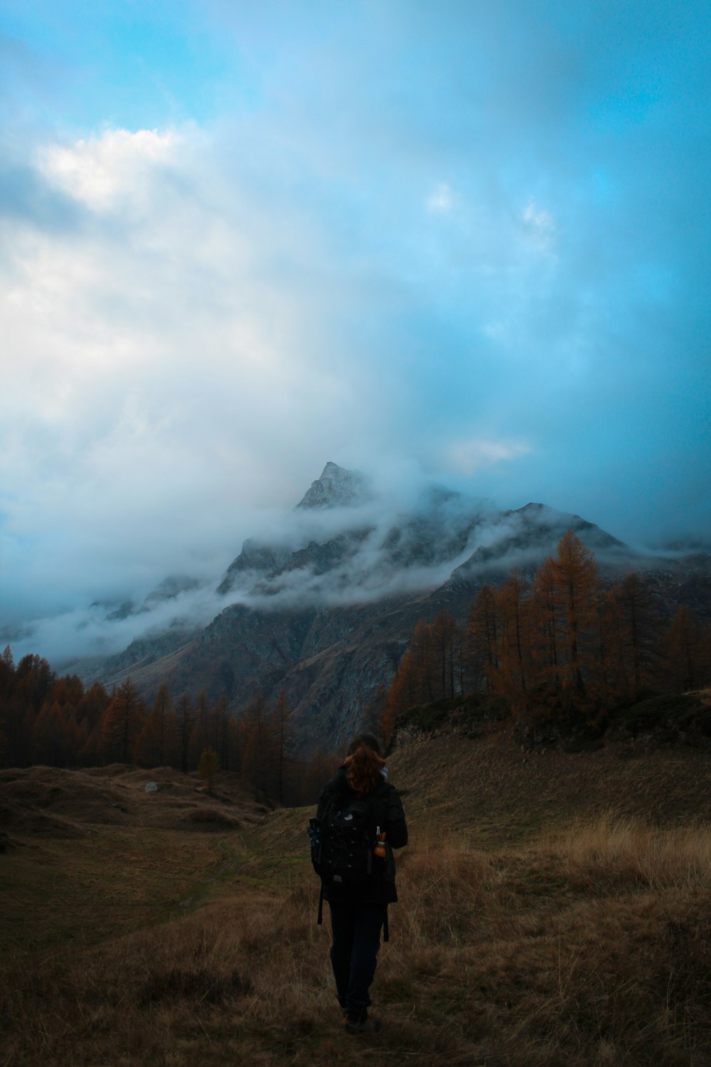 um homem de pé em uma colina com uma montanha ao fundo