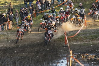 A group of riders practicing motocross techniques on a dirt track under supervision.