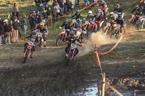 Young riders practicing motocross techniques on a dirt track under supervision.
