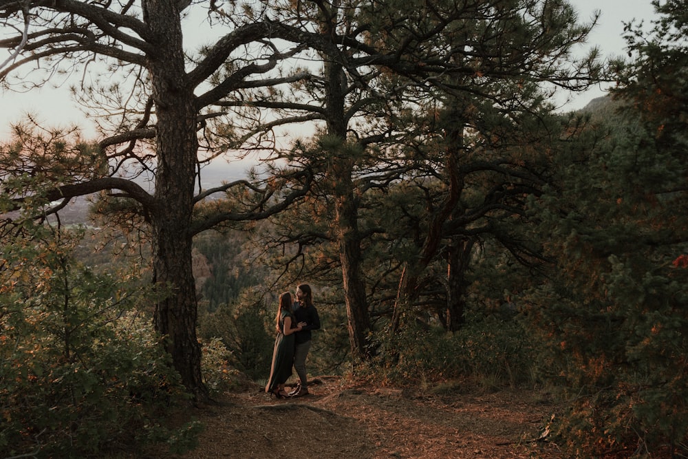 a couple of people standing on a trail in the woods