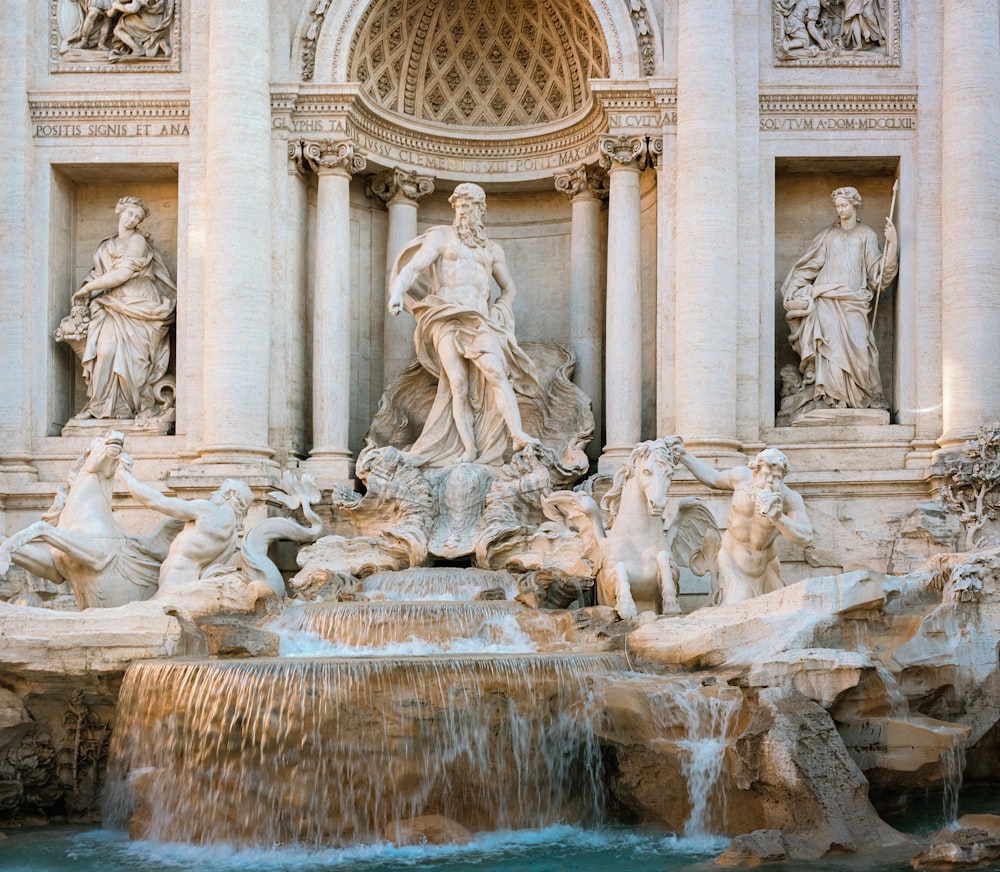 a fountain with statues in front of Trevi Fountain