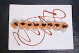 Elegant plating of sushi rolls with artistic sauce drizzles on a dark plate
