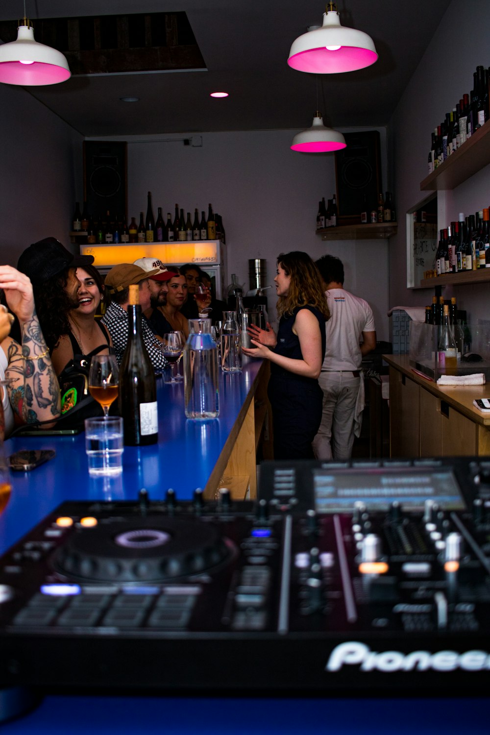 a group of people standing around a bar with bottles of alcohol