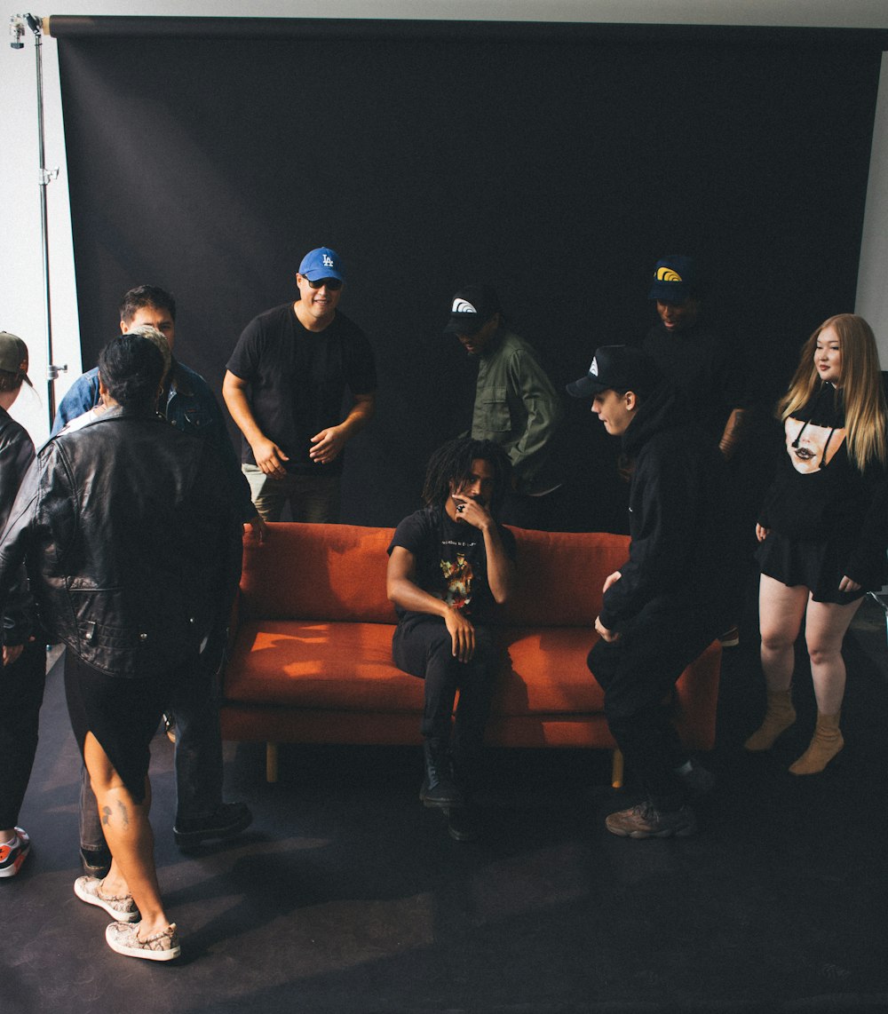 a group of people standing around a man sitting on a bench