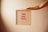 A hand extends from the right, holding a wooden-framed letter board with red letters spelling 'YOU GOT THIS' on a light pink, lined background.
