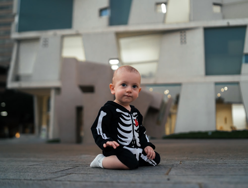 a baby sitting on a sidewalk