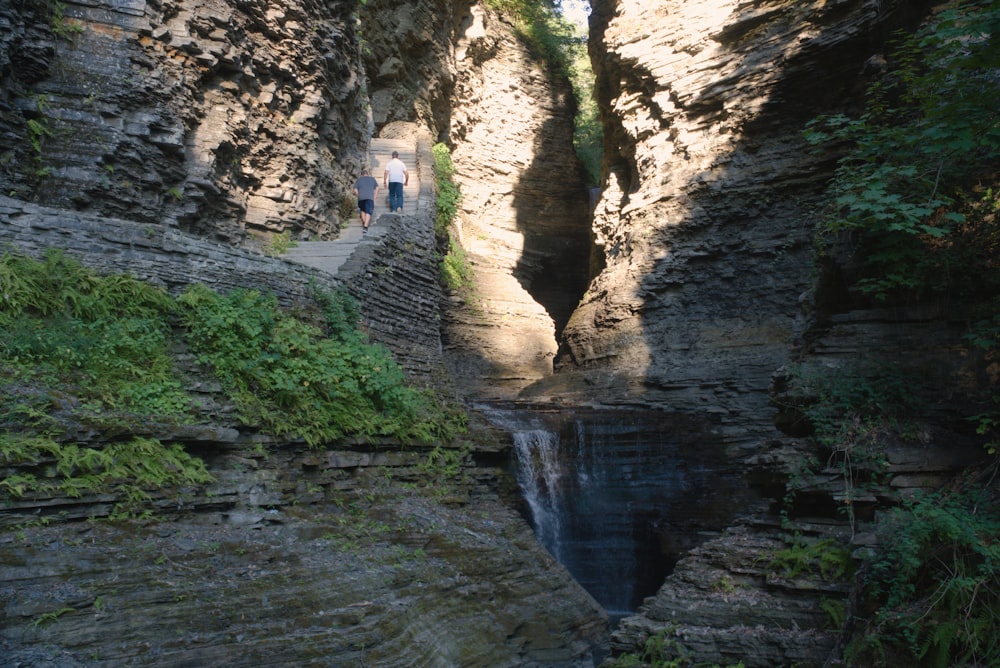 people walking on a path between rocky cliffs
