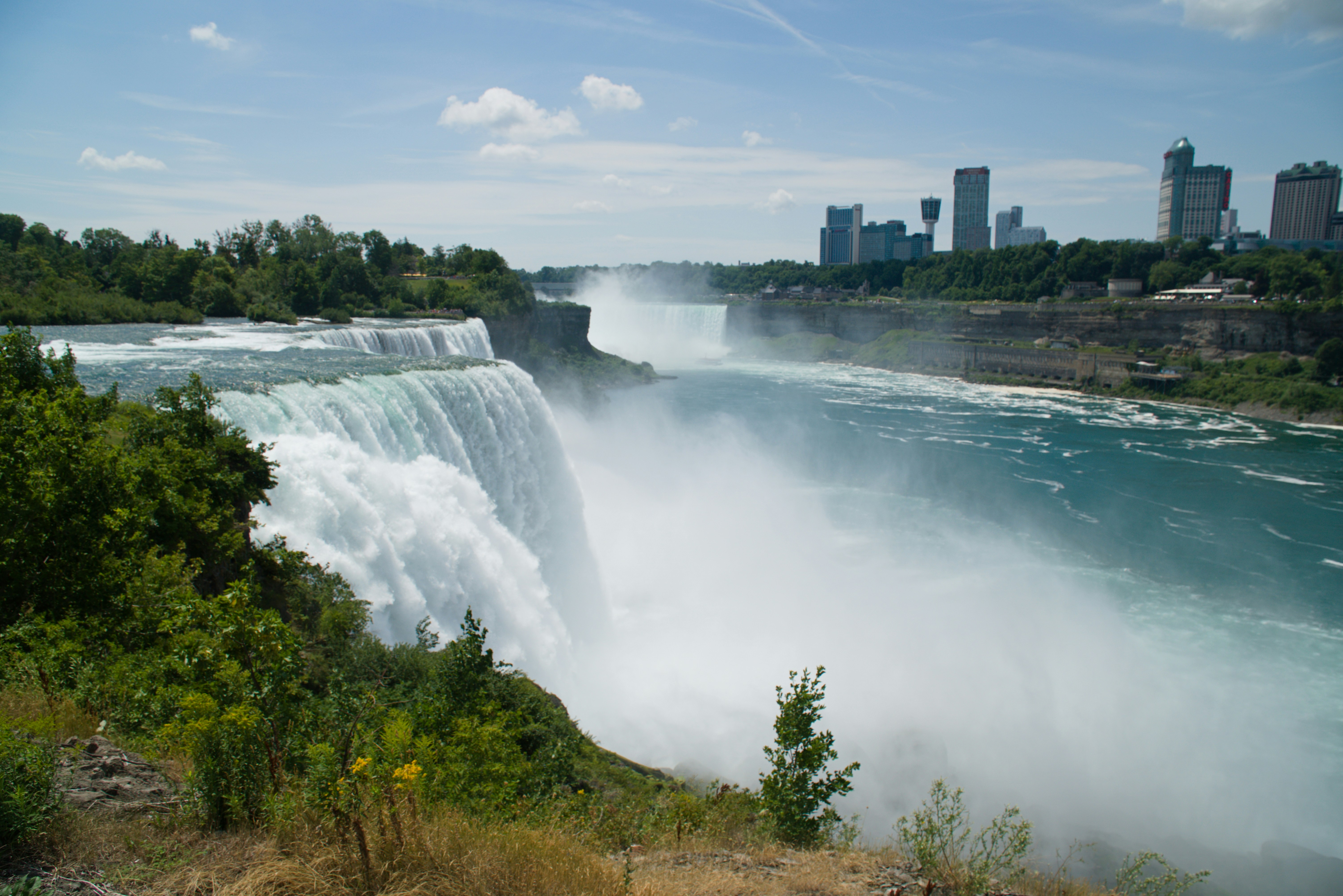 a large waterfall with a city in the background