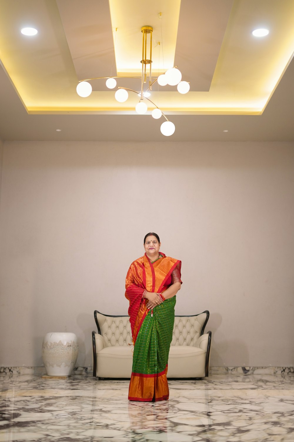a person in a robe standing in a room with a white wall and lights