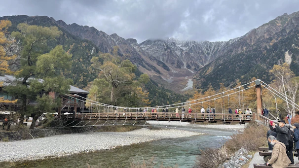 A cheerful group crossing a wooden bridge over a sparkling mountain stream.