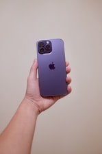 Close-up of hands holding a sleek smartphone with purple and black celucast branding in the background.