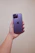 A smiling customer holding a new smartphone inside the Purptech store with a purple-themed background.
