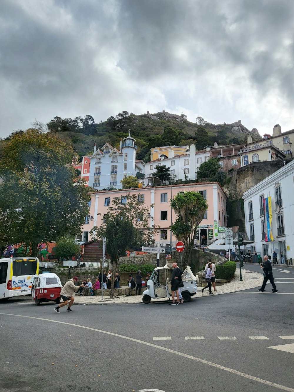 a group of people walking on a street with buildings and trees