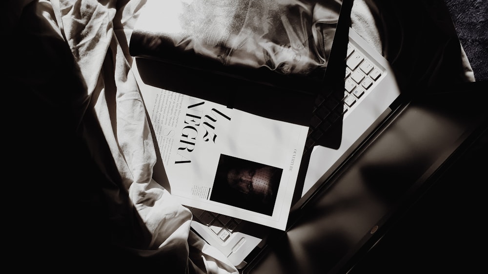 a person lying in bed with a laptop and a book