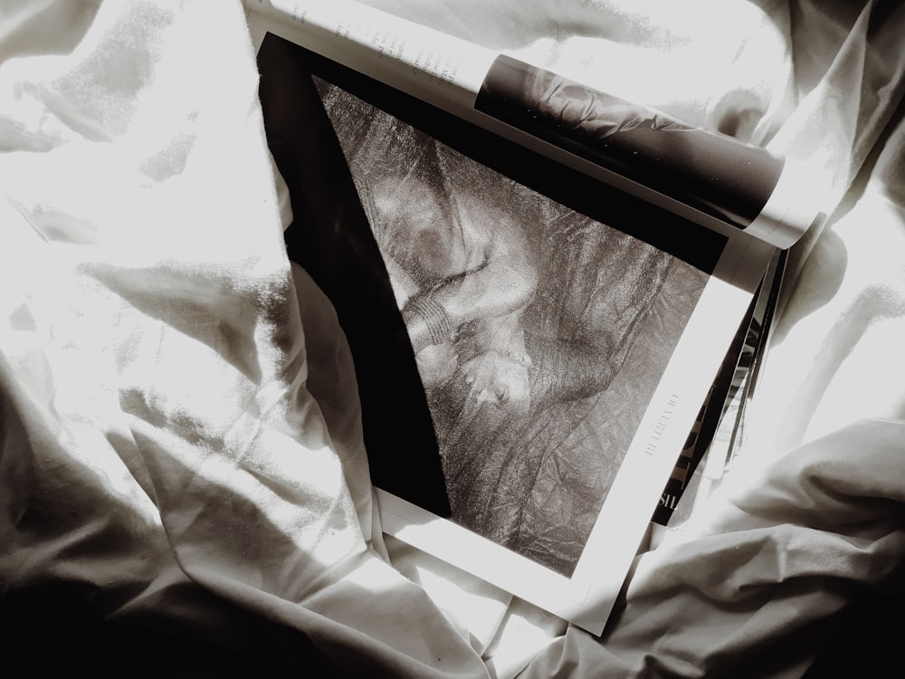 a black and white photo of a folded shirt on a bed