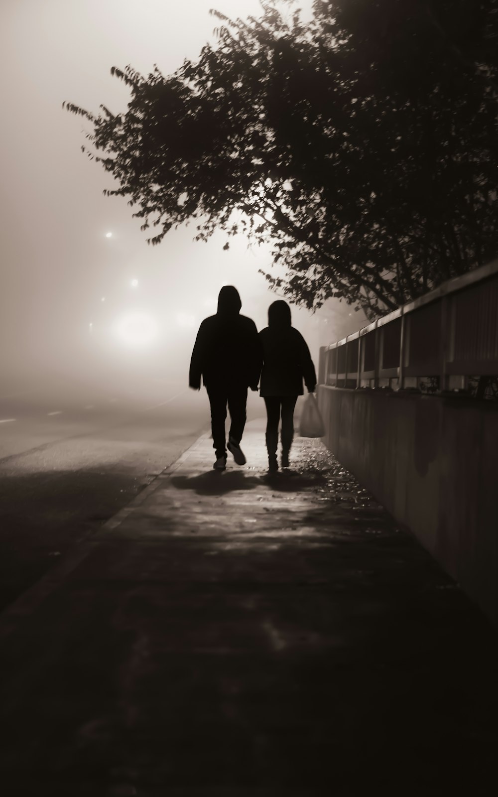 a man and woman walking on a sidewalk in the fog