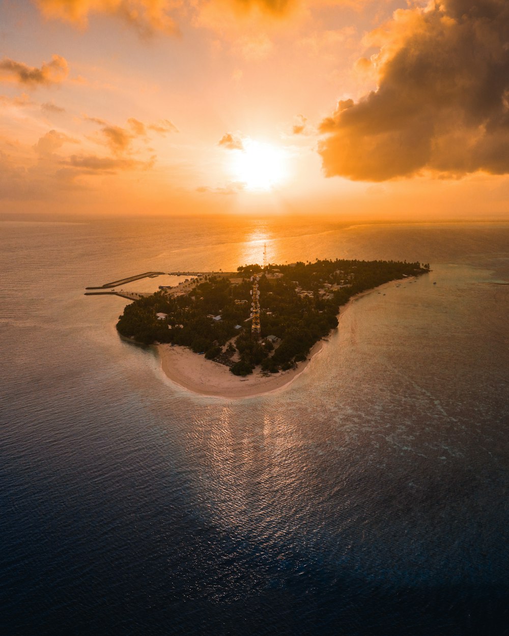 an island in the middle of the ocean with the sun setting