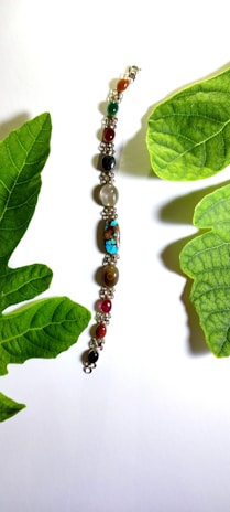 Elegant green beaded bracelets stacked together with natural leaves in the background.