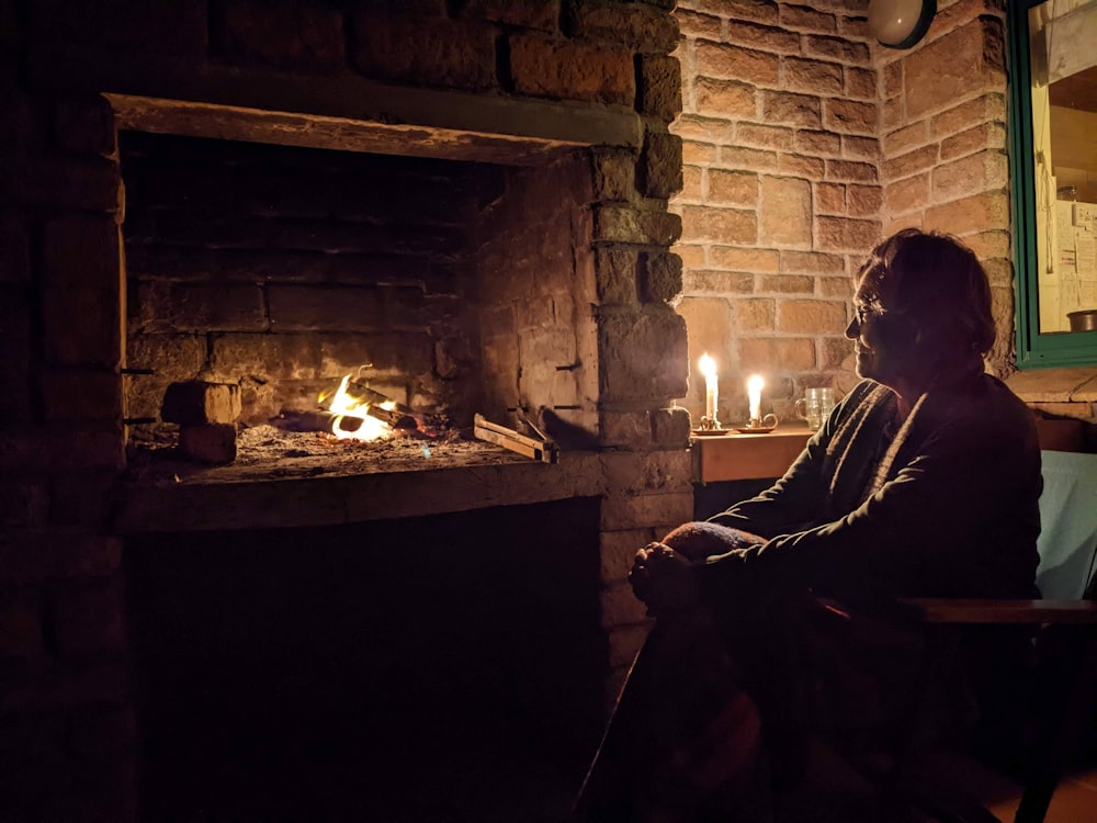 a person sitting in front of a fireplace with a candle in it