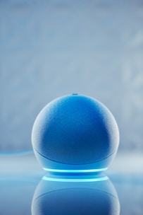 A sleek smart speaker with a matte black finish and glowing cyan accents.