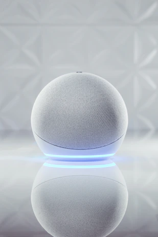 Compact smart home speaker glowing blue on a minimalist black shelf