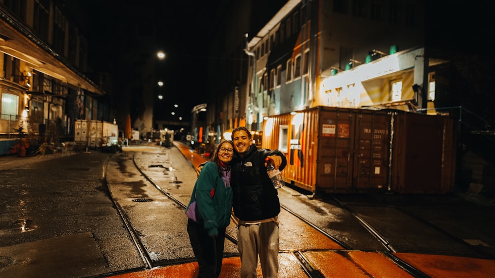a man and woman standing on a train track at night
