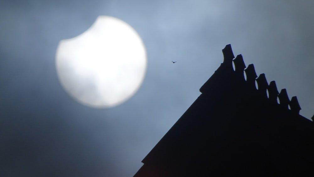 a silhouette of a building and the moon