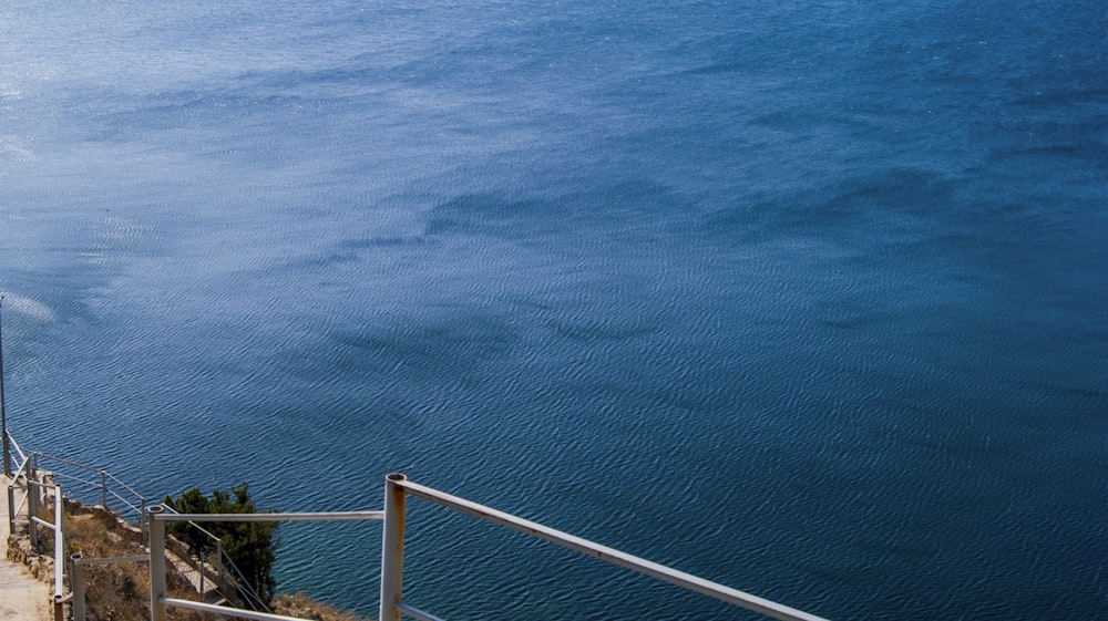 a body of water with a railing and trees on the side