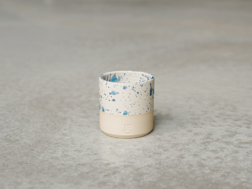 a small cup with a blue and white design on a grey surface
