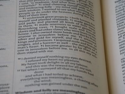 A close-up of an open book with text in a serif font on off-white pages. The content appears to be prose with numbered sections at the beginning of each paragraph. The paper shows some wear, giving it a slightly aged appearance.